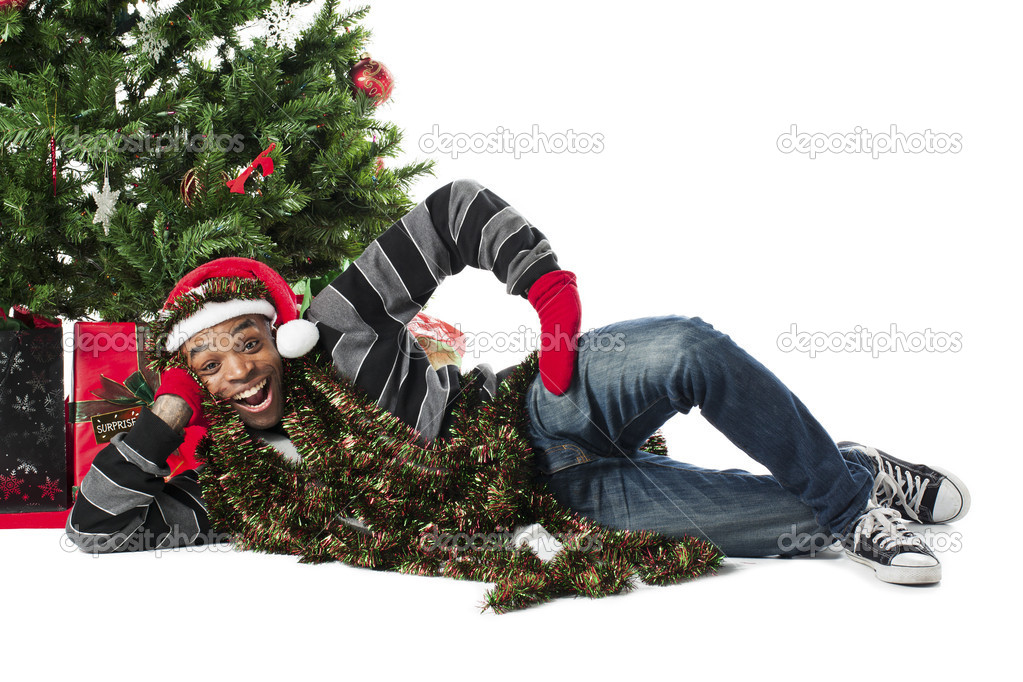happy african american man lying beside a christmas tree