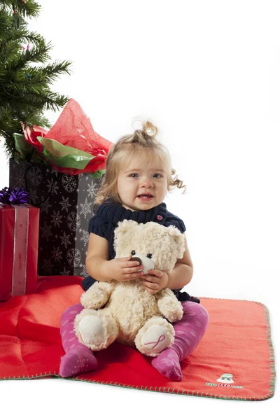 Niña sentada con osito de peluche con árbol de Navidad y cristo — Foto de Stock