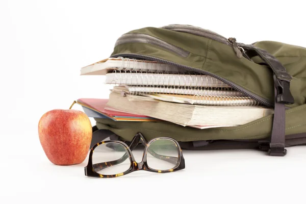 Ryggsäck med skolmaterial och apple på sidan — Stockfoto