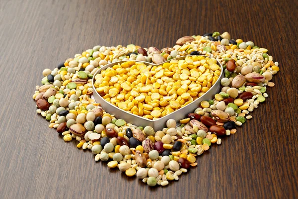 Beans in heart shape on wooden table — Stock Photo, Image