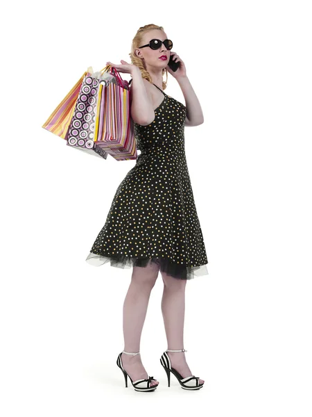 Beautiful young woman talking on cellphone while holding shoppin — Stock Photo, Image