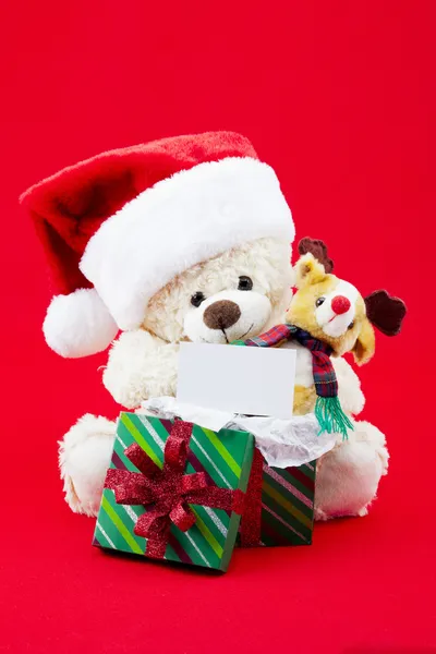 Fluffy christmas teddy bear with gift box and placard — Stock Photo, Image