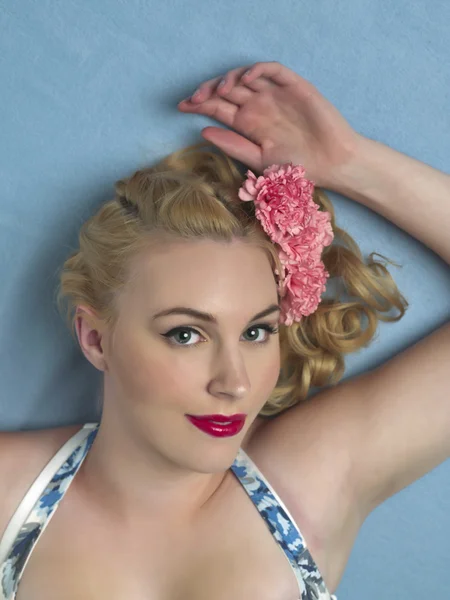 Wunderschöne blonde Frau auf blauem Hintergrund liegend — Stockfoto