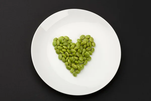 Green soya beans arranged in heart shape — Stock Photo, Image