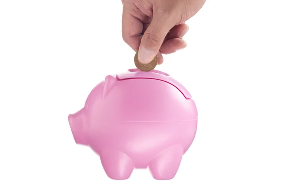 Mão com uma moeda sobre um banco piggy rosa — Fotografia de Stock