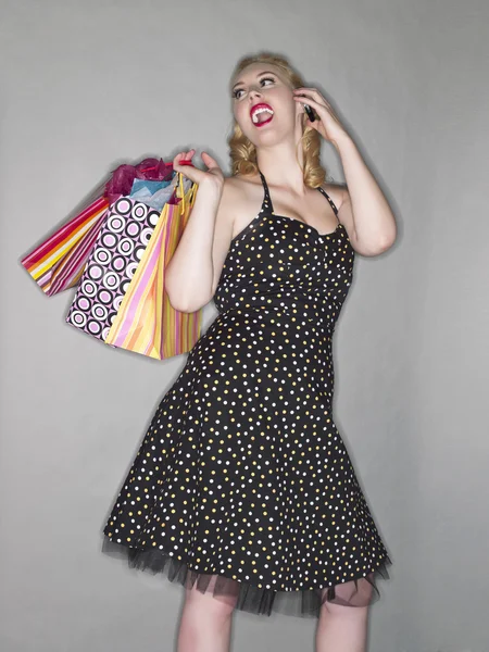 Mujer joven feliz con bolsas de compras y teléfono celular — Foto de Stock