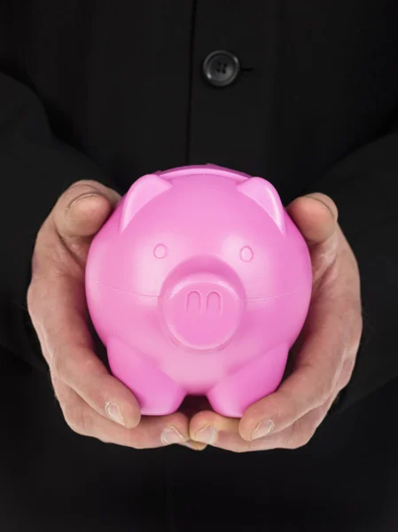 Mann hält ein rosa Sparschwein in der Hand — Stockfoto