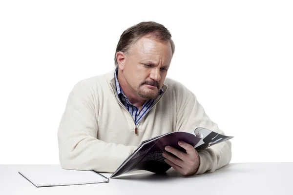Homem de negócios maduro lendo uma revista no trabalho — Fotografia de Stock