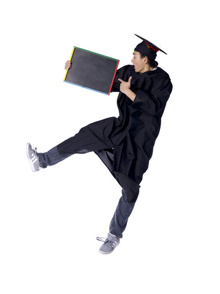 male graduate jumping while pointing on his blackboard