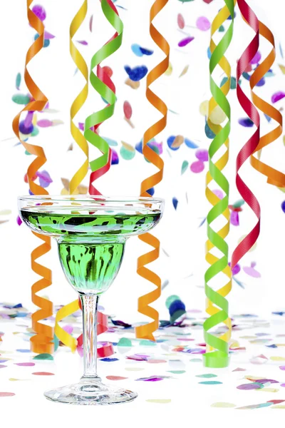 Martini glass with alcohol while streamers and confetti in backg — Stock Photo, Image