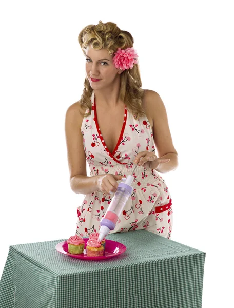 Retrato de una mujer joven poniendo crema en cupcakes — Foto de Stock