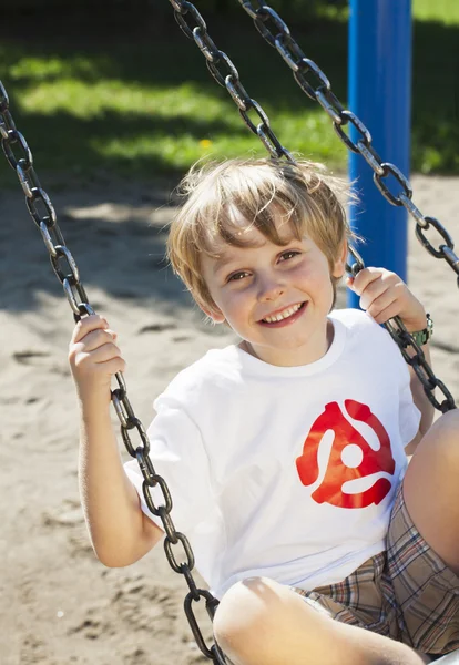 Porträtt av söt pojke svängande på swing — Stockfoto