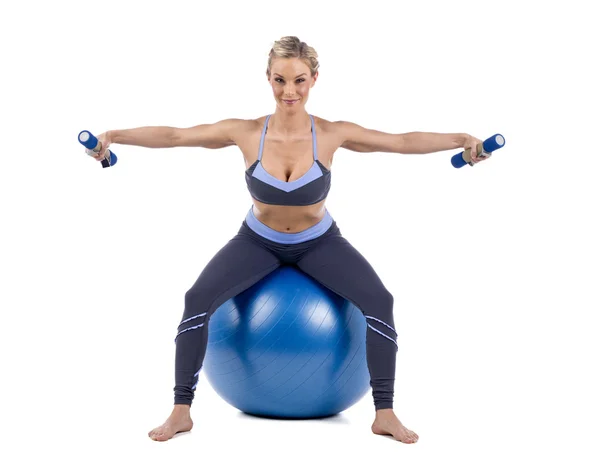 Mujer sentada en la pelota de ejercicio y levantamiento de pesas — Foto de Stock