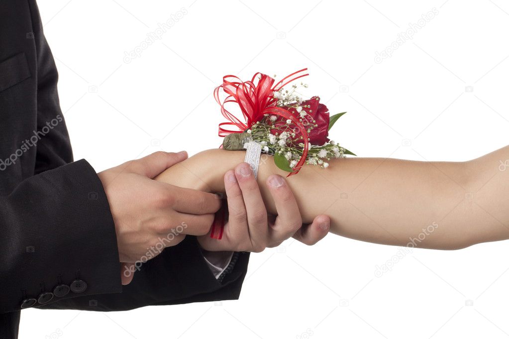 male hand holding a female hand with corsage