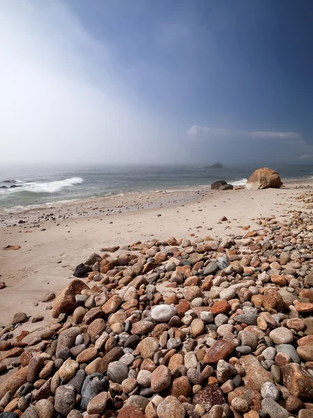 Rocks and stones at beach with sea in background — Stock Photo, Image