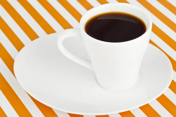 Una taza de café oscuro en un platillo — Foto de Stock