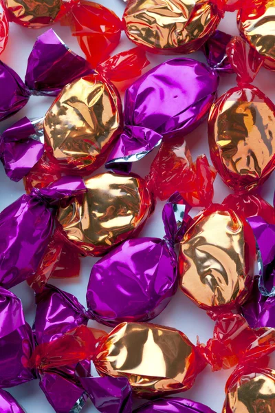 Vista de perto de dourado e roxo doces duros organizar aleatoriamente — Fotografia de Stock