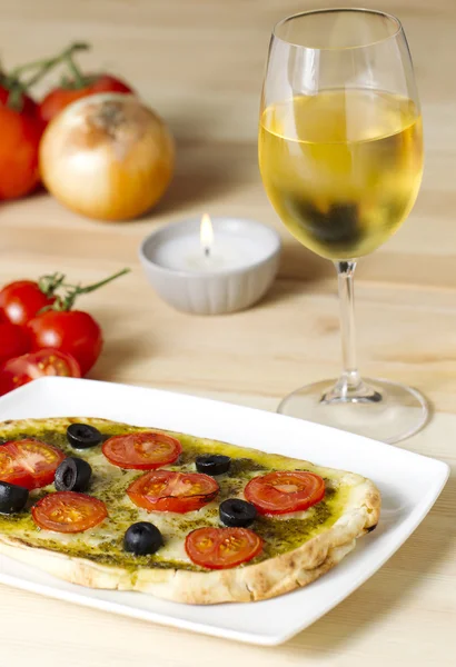 Pesto pizza with tomatoes and black olives — Stock Photo, Image