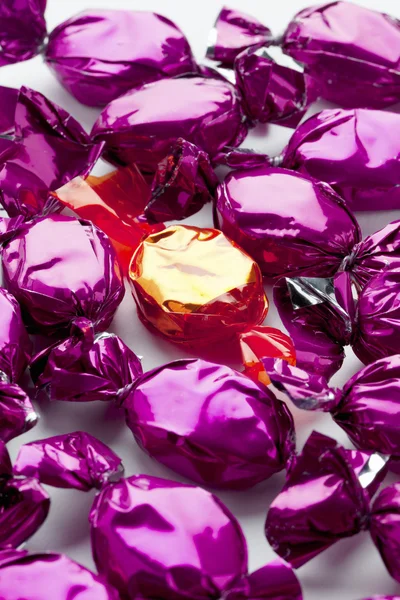 Vue d'un bonbon doré entouré de bonbons brillants violets — Photo