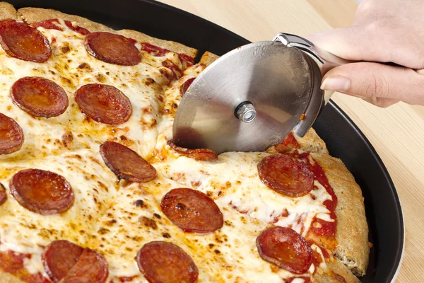 Slicing of pizza on cooking tray — Stock Photo, Image