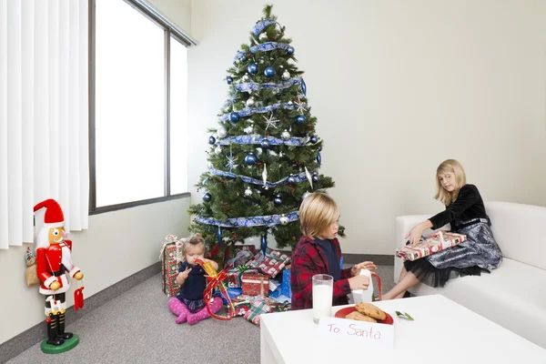 View of sibling packing christmas gift box in a drawing room — Stock Photo, Image