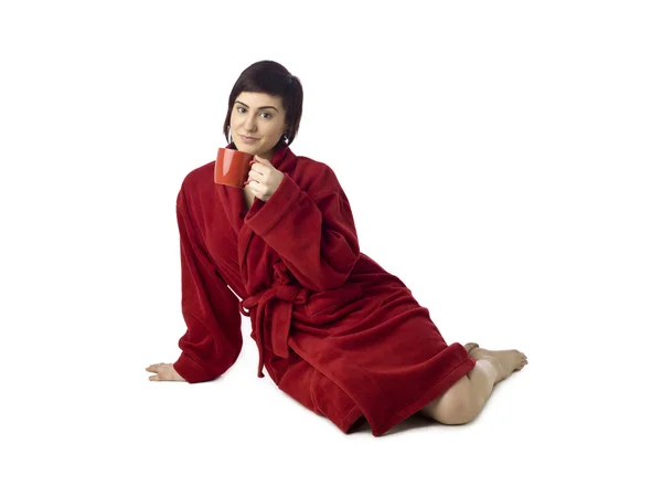 A woman wearing a red robe drinking a coffee — Stock Photo, Image