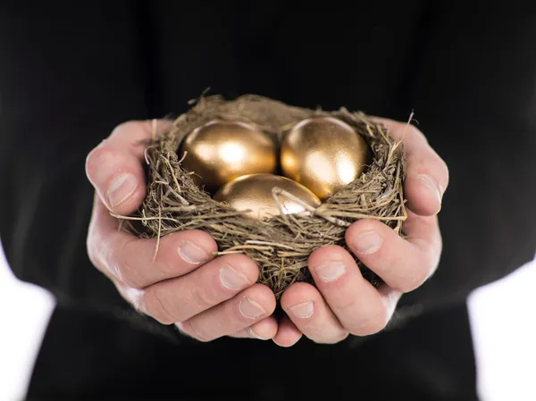 Podnikatel drží hnízdo s zlatá vejce — Stock fotografie