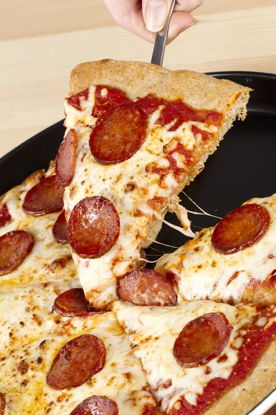 Выбираю кусок пиццы с пепперони — стоковое фото