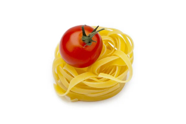 Nido de fideos fettuccine con un tomate —  Fotos de Stock