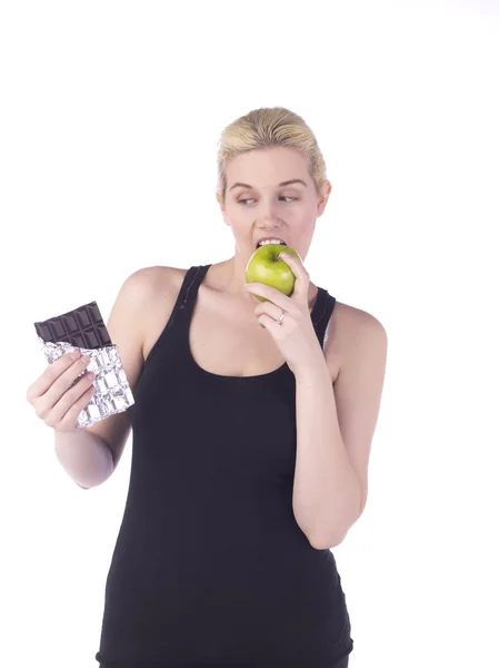 Egy sportos nő úgy dönt, hogy enni egy almát, mint a csokoládé — Stock Fotó