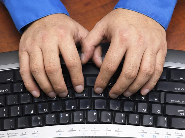 Close up shot of a person typing on keyboard on wooden desk — Stock Photo, Image