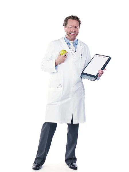 若い医者は青リンゴとクリップボードを保持笑みを浮かべてください。 — ストック写真