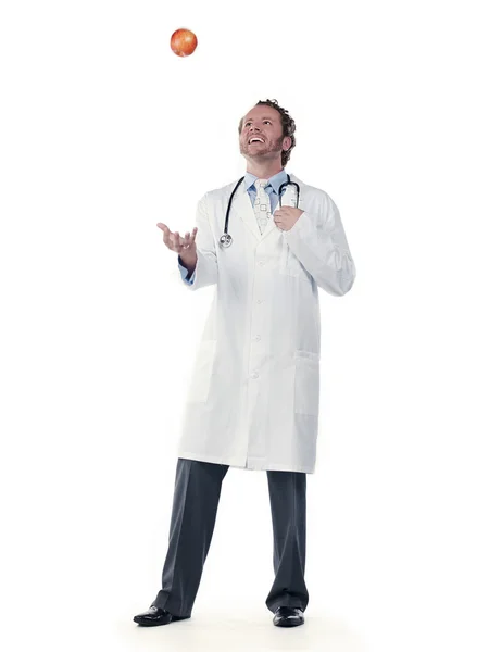 Young doctor tossing an apple — Stock Photo, Image