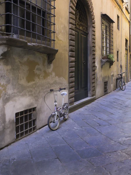 Cykel på stenmuren i lilla toskanska staden — Stockfoto