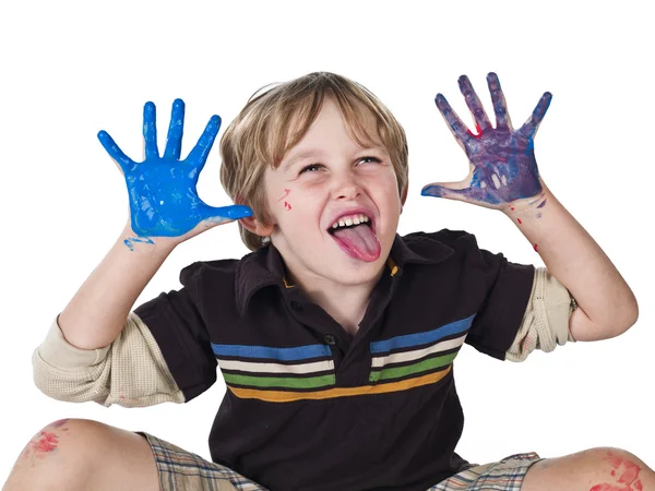 Jongen met verf op zijn handen en tong uitsteekt — Stockfoto