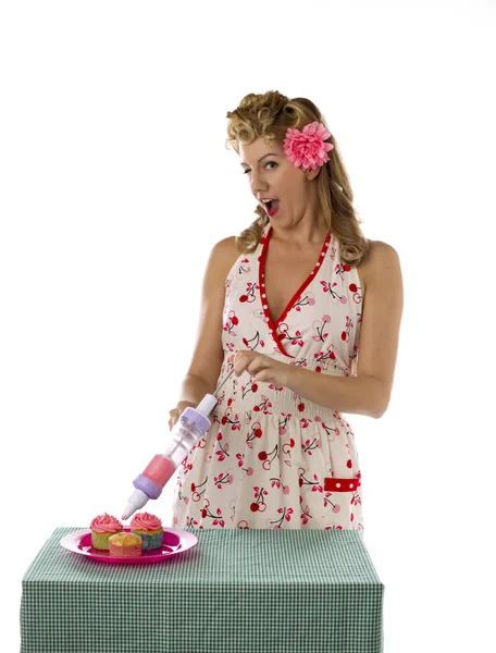 Cheerful young woman putting whipped cream on cupcakes — Stock Photo, Image