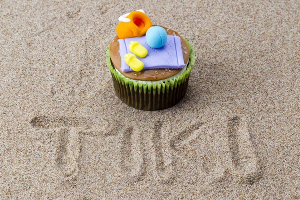 View of cupcake with decorative miniatures toppings on sand with — Stock Photo, Image