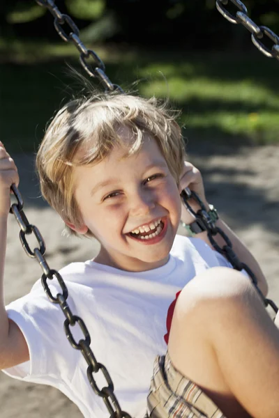 Närbild på en glad pojke svängande på swing — Stockfoto