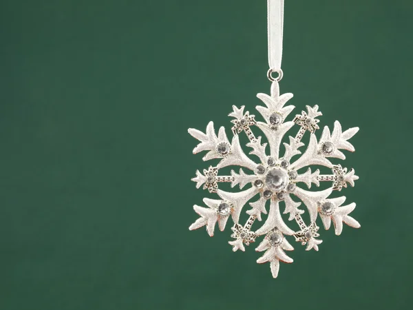 Snowflakes pattern bauble hanging over green background — Stock Photo, Image