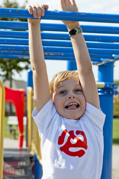 424 glimlachend jongetje opknoping op monkey bars — Stockfoto