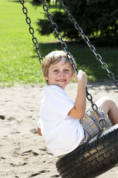 745 Seitenansicht eines Jungen, der auf einer Reifenschaukel schwingt — Stockfoto