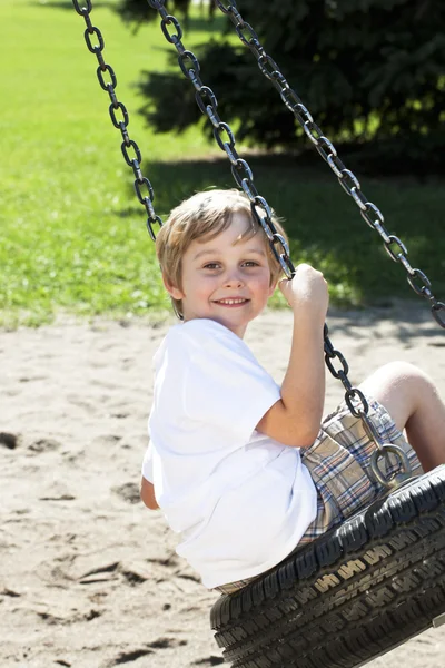 Sidovy av en pojke som svängande på däck swing — Stockfoto