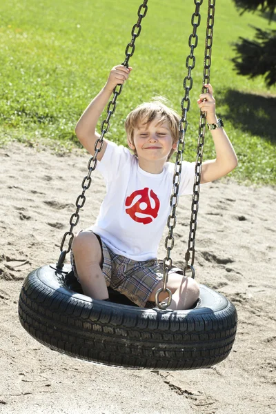 808 cute elementary boy sitting on swing — Stock Photo, Image