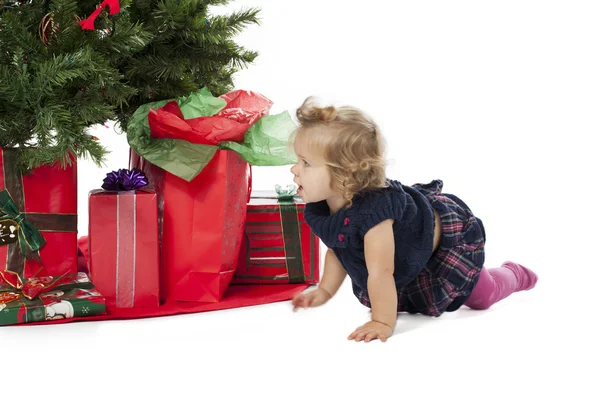 Ein kleines Mädchen krabbelt am Weihnachtsbaum vorbei — Stockfoto