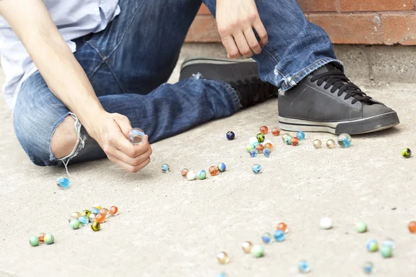 Un chico jugando canicas en la calle — Foto de Stock