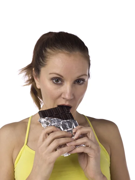 Una mujer deportiva comiendo barra de chocolate —  Fotos de Stock