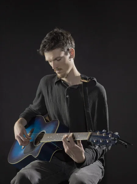 A male guitarist tuning the guitar — Stock Photo, Image