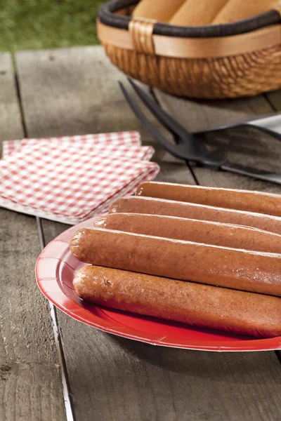 Un plato de perritos calientes con una cesta de bollos en el fondo —  Fotos de Stock