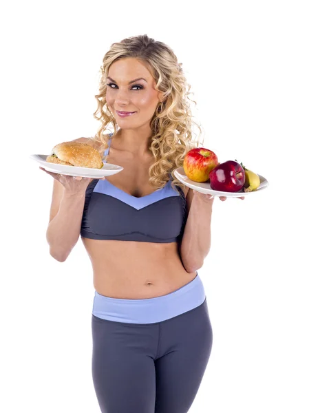 Una mujer deportiva sexy con frutas y hamburguesa — Foto de Stock
