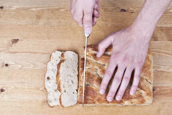 Uma mão com faca cortando o pão — Fotografia de Stock